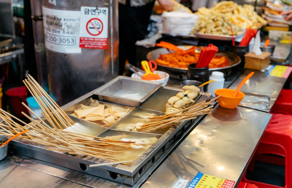 A traditional Korean market stall offers eomuk skewers simmering in hot broth alongside other popular street foods.