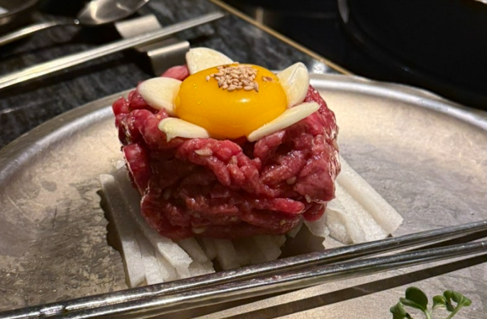 Yukhoe (육회), seasoned raw beef served over julienned pear and topped with an egg yolk and sesame seeds.