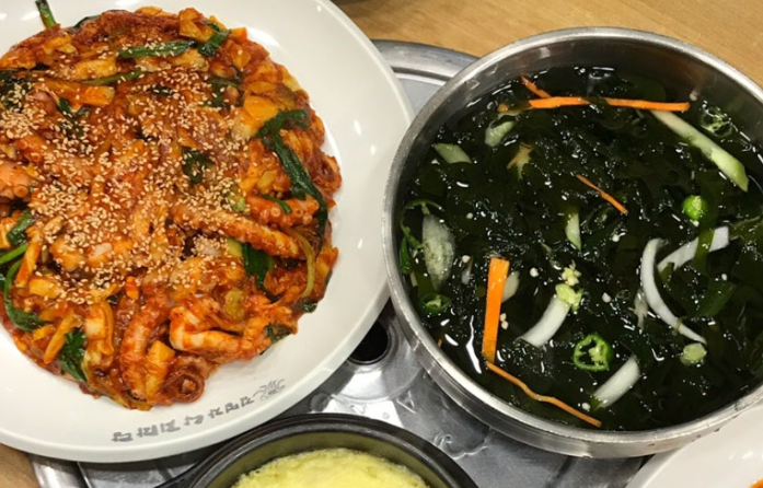 Spicy nakji-bokkeum (낙지볶음) served with chilled seaweed soup (미역냉국), a refreshing side to balance the heat.