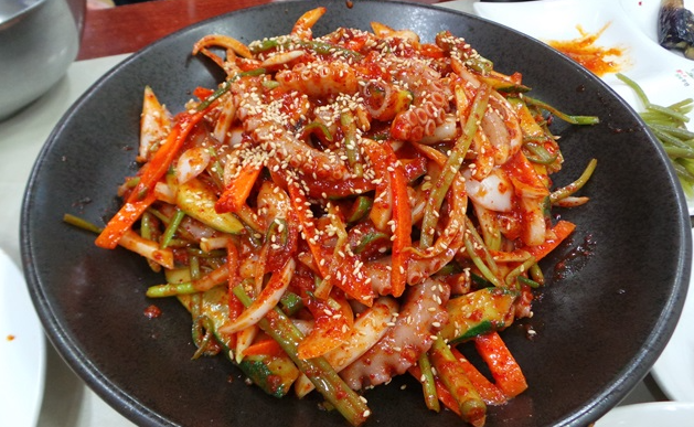 Nakji-chomuchim (낙지초무침), a spicy, tangy octopus salad tossed with crisp vegetables and topped with sesame seeds.
