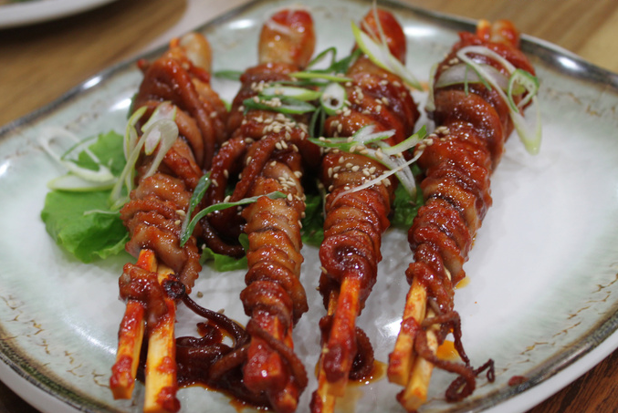 Nakji-horonggui (낙지호롱구이), octopus wrapped around skewers, grilled, and coated in a spicy sauce.