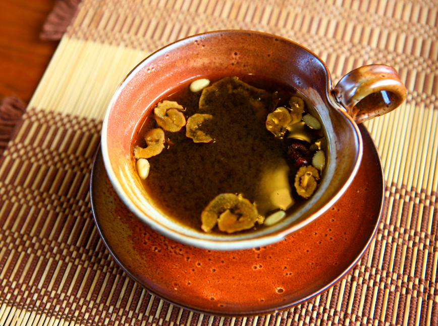 A cup of traditional Korean jujube tea (daechucha) is garnished with dried jujube slices and pine nuts.