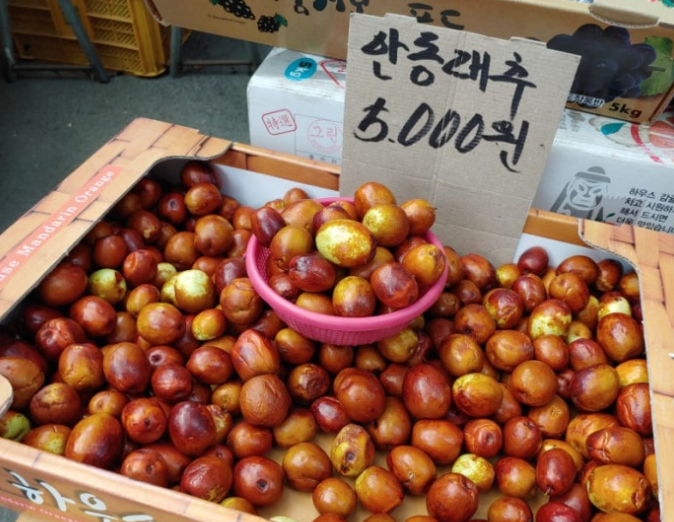 Fresh Korean jujubes (daechu) are displayed in a box at a traditional market